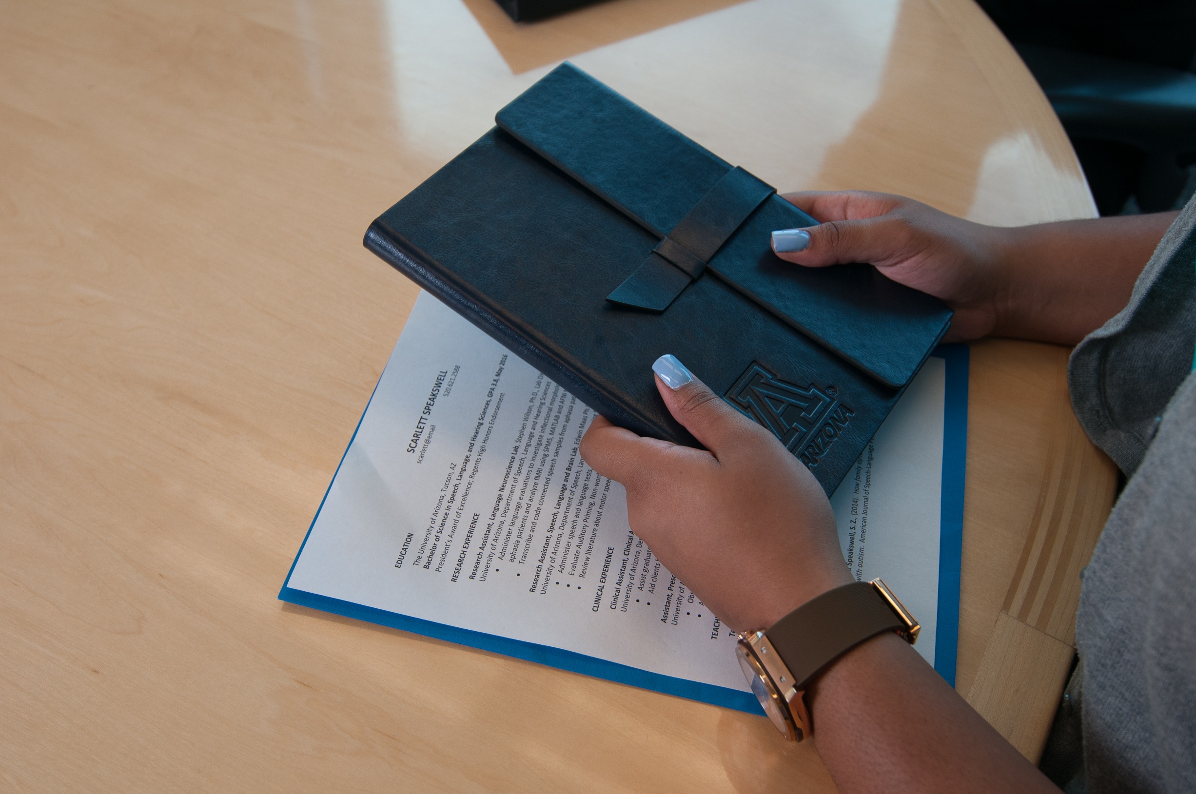 A person holding a black planner with the University of Arizona "A" logo on it.