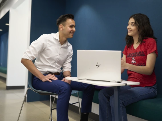 Two people sitting across from each other talking and smiling.