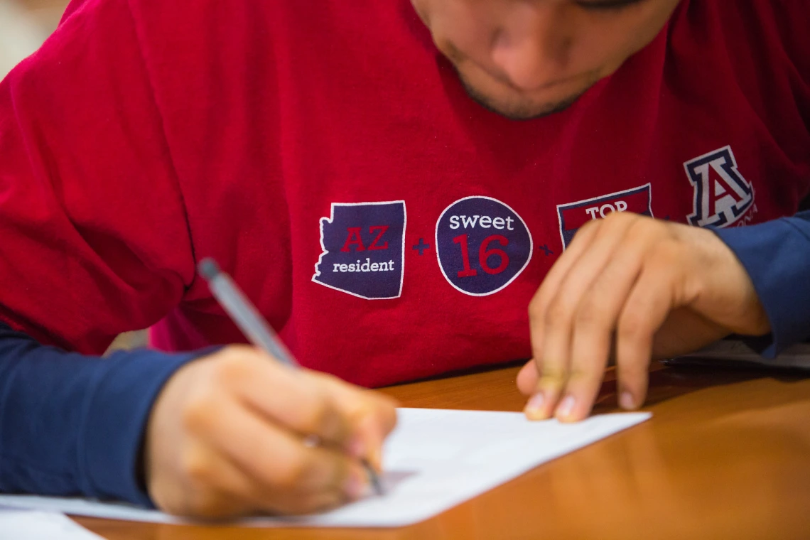 A person holding a pencil writing something.