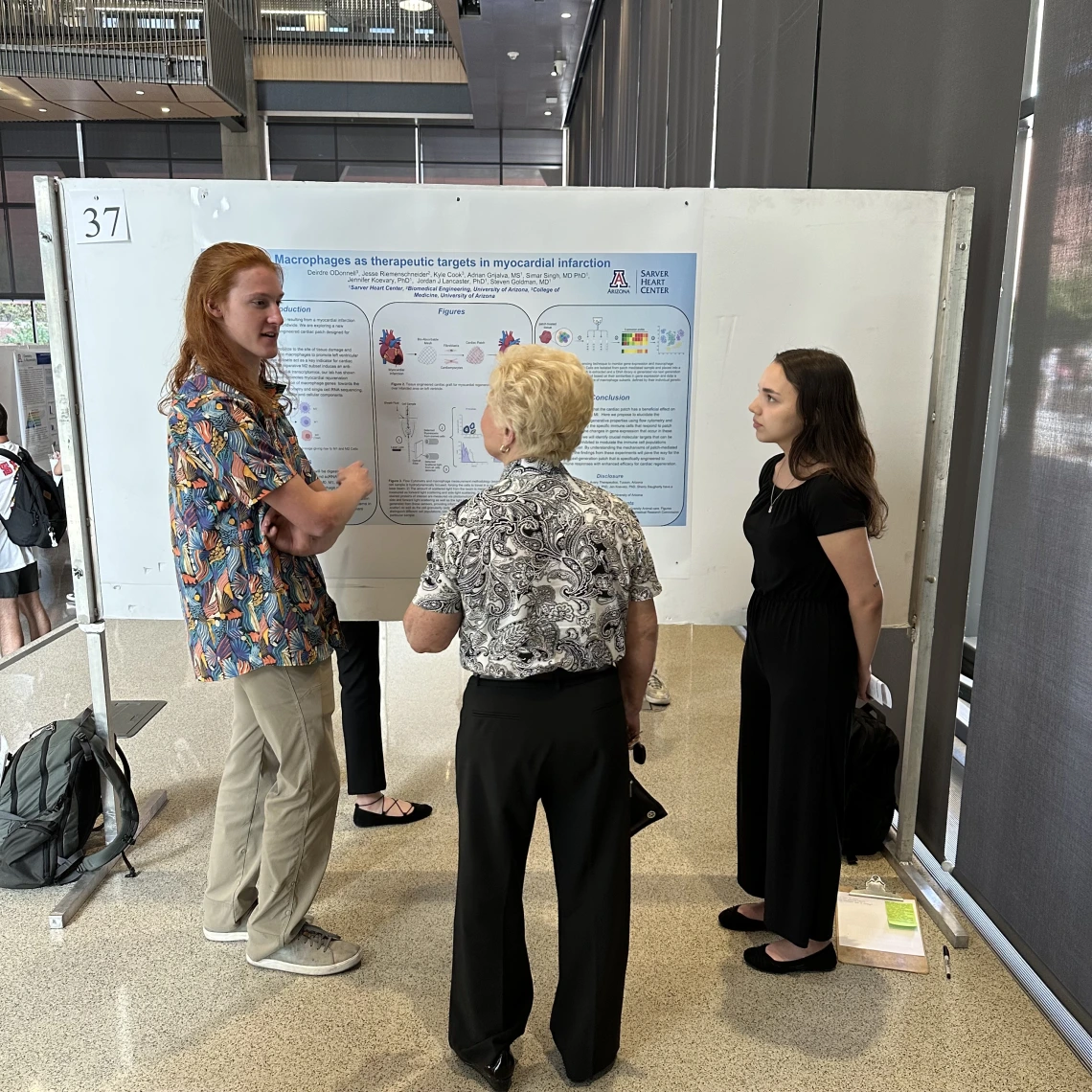 Three people standing around a research poster.